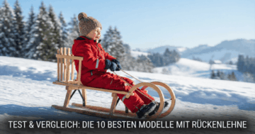 Kind sitzt warm eingepackt auf einem Holzschlitten mit Rückenlehne im verschneiten Winterberg.